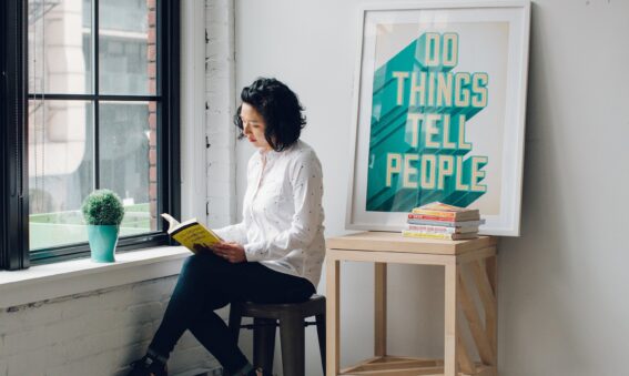 Women sitting next to sign that says 'Do Things. Tell People' to show personal branding